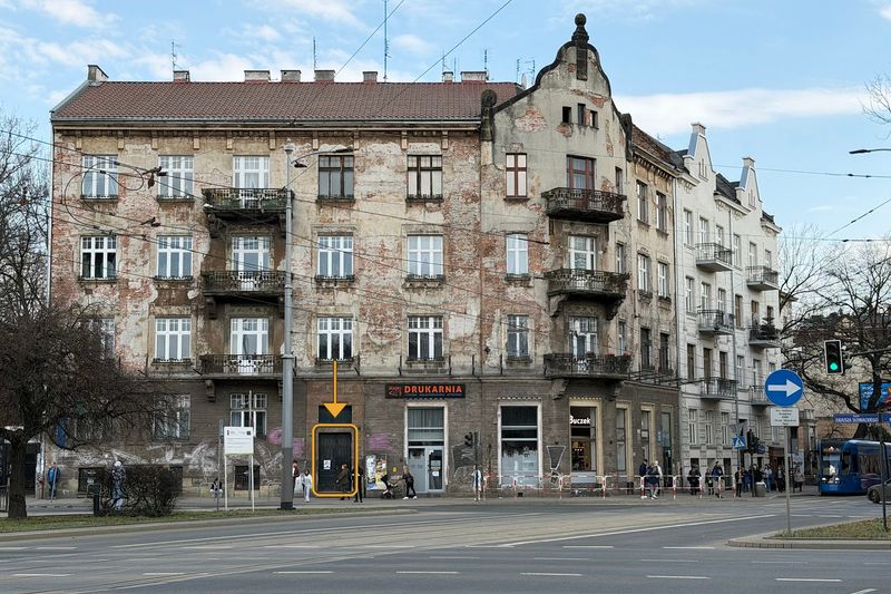 Kamienica przy Al. Słowackiego 1 od strony placu Inwalidów; wejście to ciemne drzwi na lewo od drukarni, zaznaczone strzałką